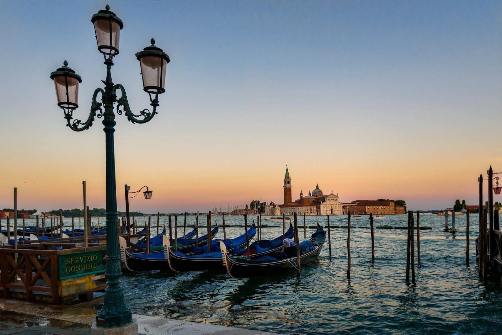 green metal post in front of the body of ocean with boats during twilight