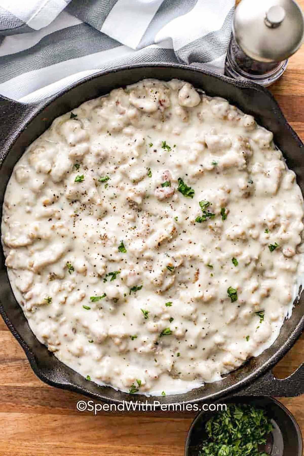 a skillet of sausage gravy on a wood board