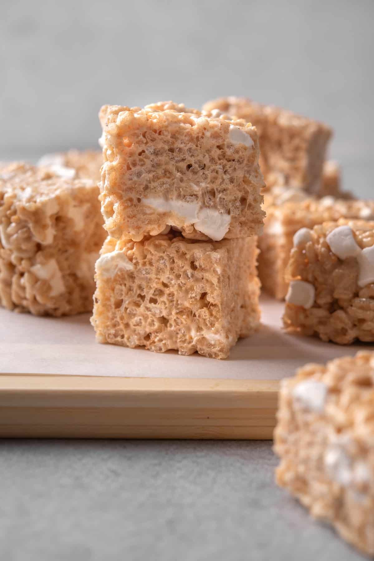 Brown butter rice krispie treats stacked on a wooden cutting board.