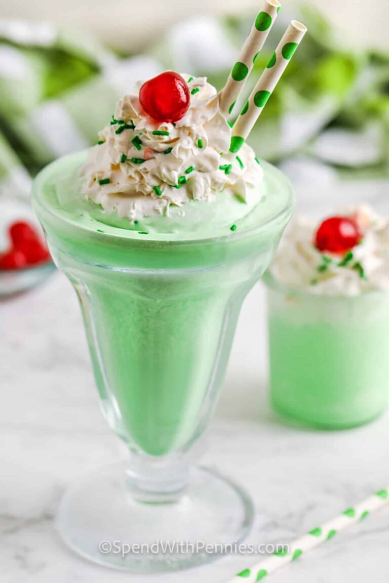 A large and a small shamrock shake with whipped topping, green sprinkles, a cherry, and straws.