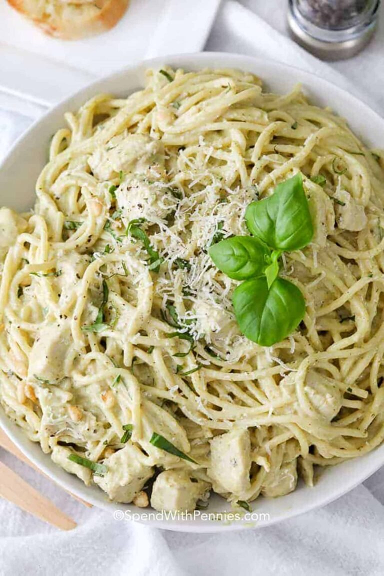 creamy pesto pasta in a white serving bowl garnished with basil