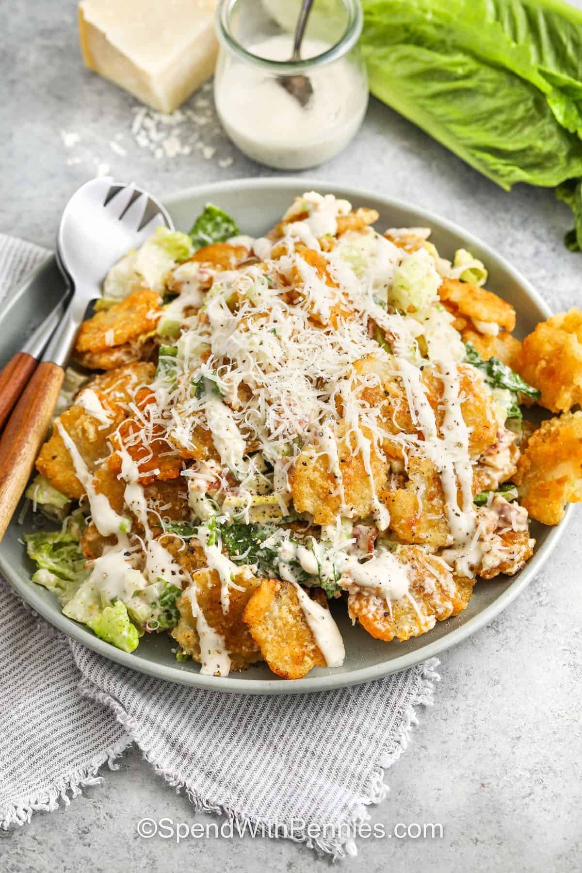 plated Crispy Tater Caesar Salad with cheese and dressing over top