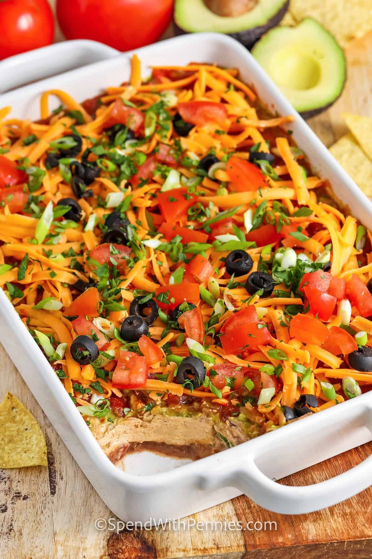 easy 7 Layer Dip in a dish with a scoop taken out
