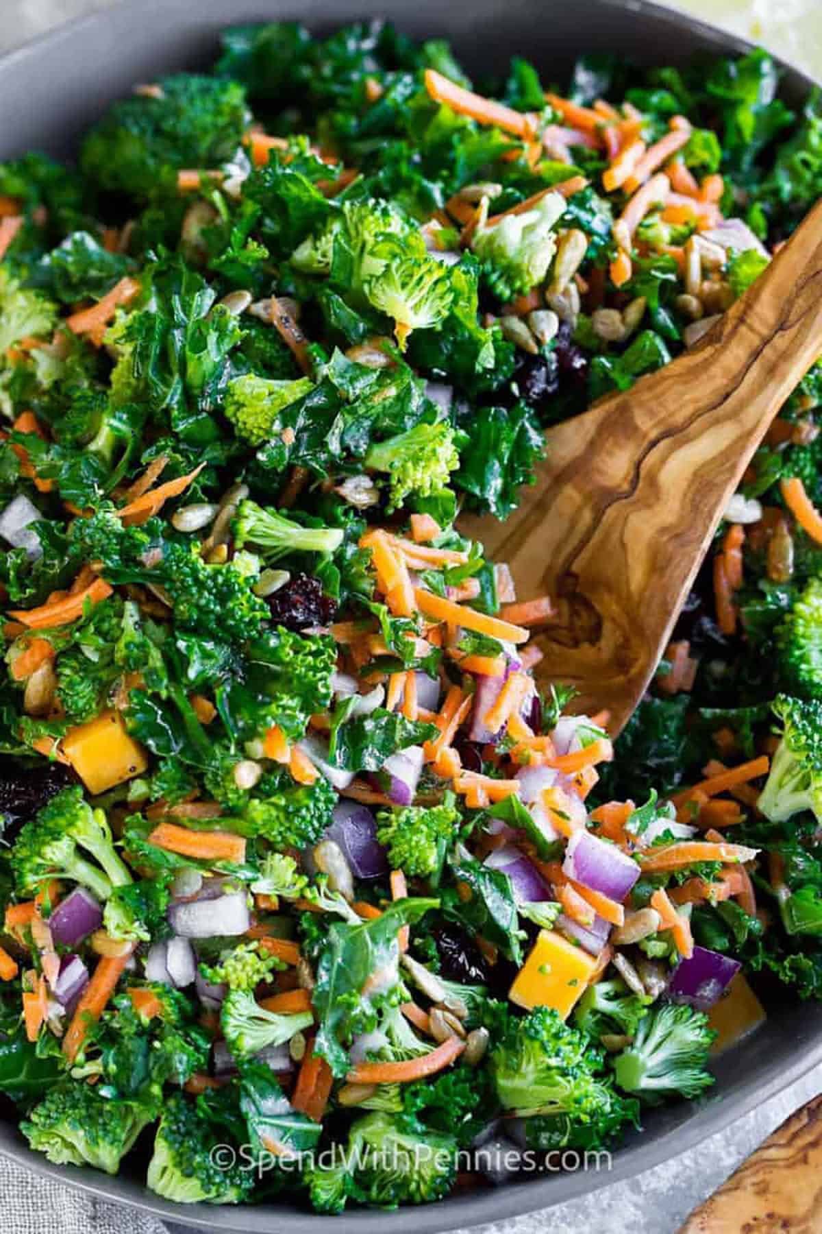 Easy Kale Salad with Fresh Lemon Dressing in a bowl with a wooden spoon